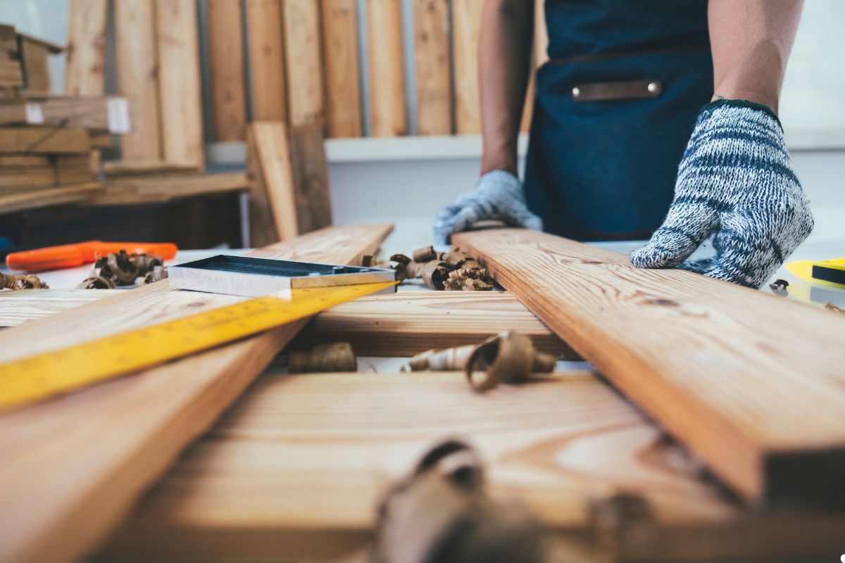 A man focused on crafting a wooden plank, using tools to shape and refine the wood.